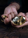 Close-up of hands holding a small brass tray with coins and a ring.