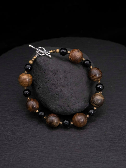 Beaded bracelet with brown and black beads on a dark stone surface