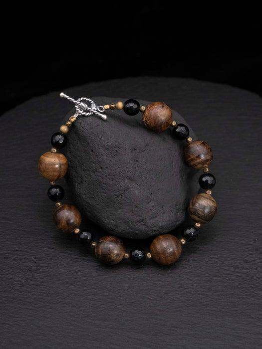 Beaded bracelet with brown and black beads on a dark stone surface