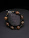 Beaded bracelet with brown and black beads on a dark stone surface