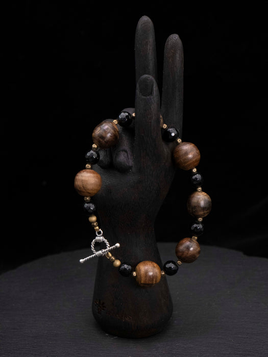 Bracelet with wooden beads on a black mannequin hand against a dark background