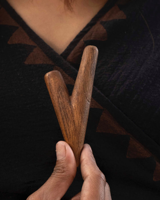 Person holding two wooden sticks against a dark background