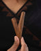 Person holding two wooden sticks against a dark background