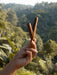 Hand holding a wooden tool against a forest background