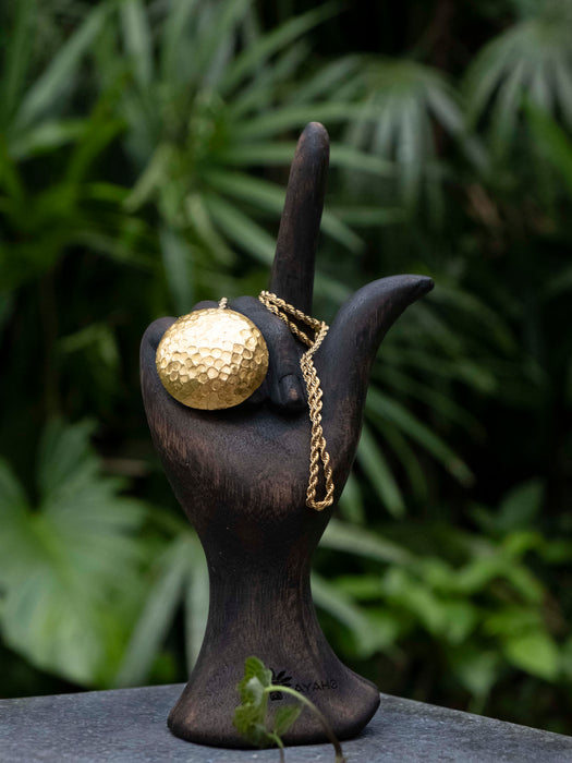 Decorative object with a gold sphere and chain on a dark background