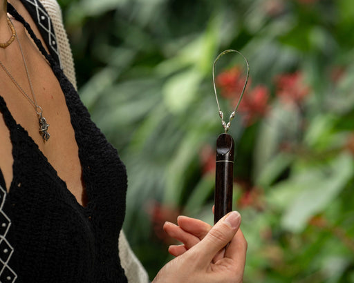 Sustainable bamboo tongue scraper with smooth rounded edge, placed beside a toothbrush and natural toothpaste."