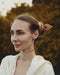 Delicate wooden hair clip securing a wispy bun, demonstrating its grip and the artisan’s carved leaf detailing.