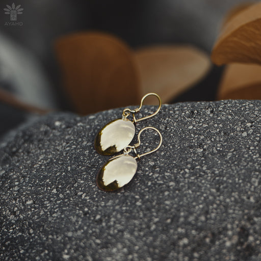 Close-up of artisan-crafted bronze earrings with circular mirrors, showcasing intricate tribal engravings on textured metal