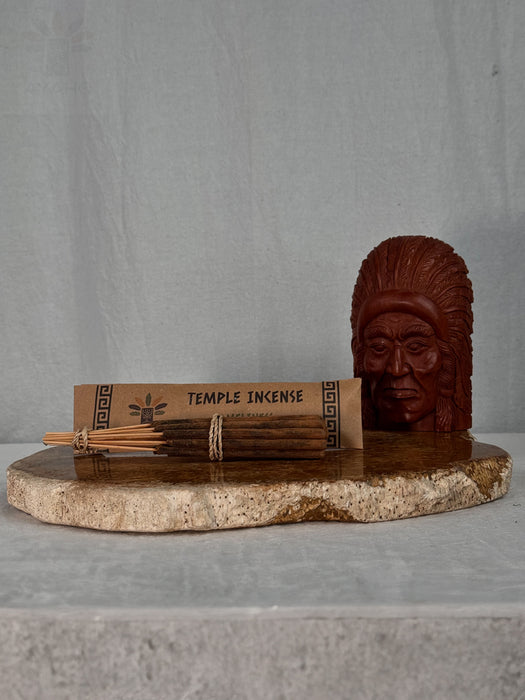 Temple incense with a wooden sculpture on a stone platform against a gray background