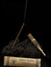 Incense sticks on a bed of charcoal with a labeled incense package against a black background