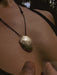 Close-up of a necklace with a textured pendant on a person's neck.