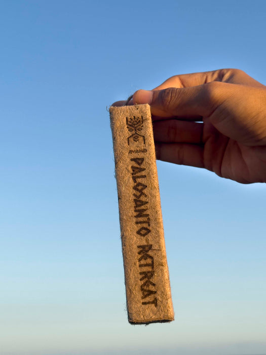 Hand holding a Palo Santorit stick against a clear blue sky