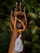 Wooden mala beads with a tassel on a wooden stand against a blurred green background