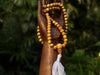 Wooden hand holding a string of beads with a blurred green background