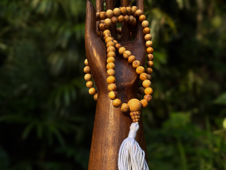 Wooden hand holding a string of beads with a blurred green background