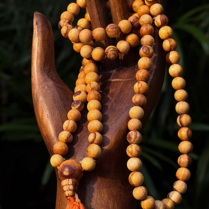 Wooden prayer beads with a wooden holder against a dark background