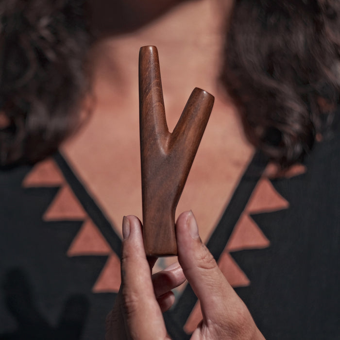 Wooden peace sign held by a person against a patterned background