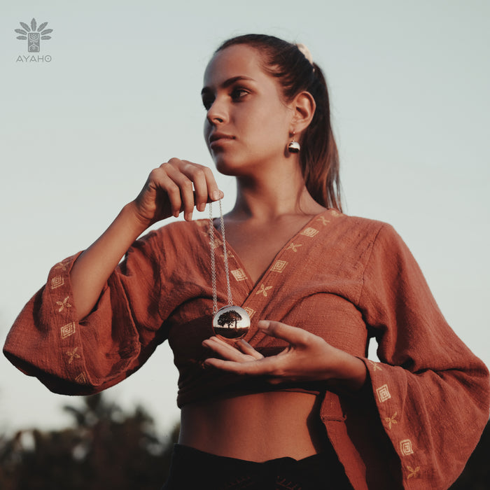 Woman holding a necklace with a pendant against a blurred natural background