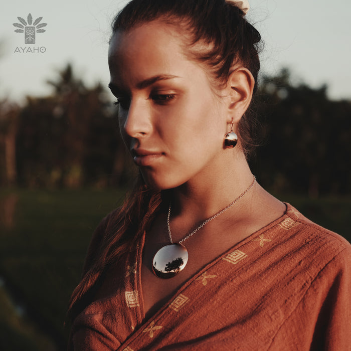 Woman wearing a brown traditional outfit with jewelry in an outdoor setting