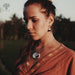 Woman wearing a brown traditional outfit with jewelry in an outdoor setting