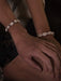 Close-up of hands wearing shell bracelets on a dark background