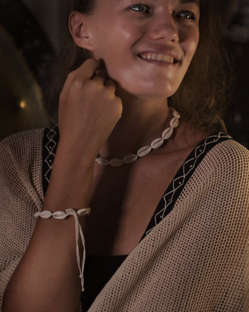 Woman wearing a necklace and bracelet with a dark background