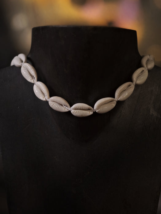 Necklace made of cowrie shells on a black mannequin with a blurred background