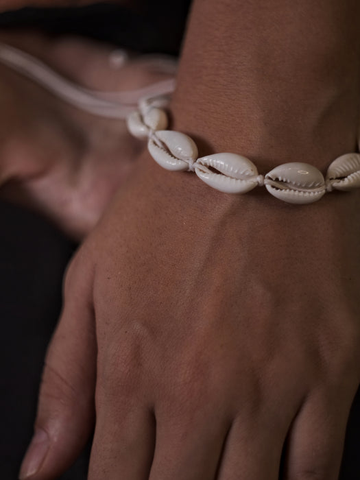 Close-up of a shell anklet on a person's ankle with a blurred background