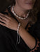 Person wearing a shell bracelet and necklace against a dark background