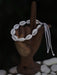 Bracelet made of cowrie shells on a wooden hand with a dark background