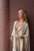 Woman wearing a patterned robe against a textured brown wall