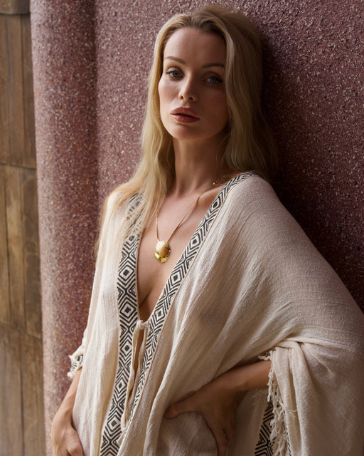 Woman in a flowing garment against a textured wall