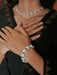 Person wearing a shell bracelet and necklace on a dark background