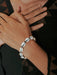 Close-up of a hand wearing a white beaded bracelet on a dark background