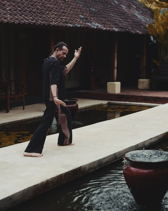 Person practicing yoga by a poolside with traditional architecture in the background
