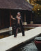 Person practicing martial arts on a platform by a pool with traditional architecture in the background