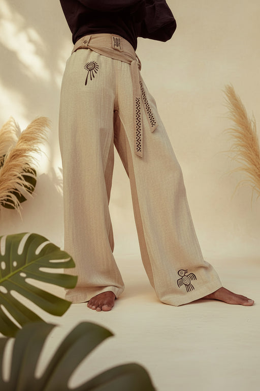 Person wearing beige embroidered pants standing on stone steps outdoors.