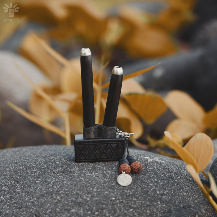 Black and silver hair styling tool with accessories on a textured surface with blurred natural background