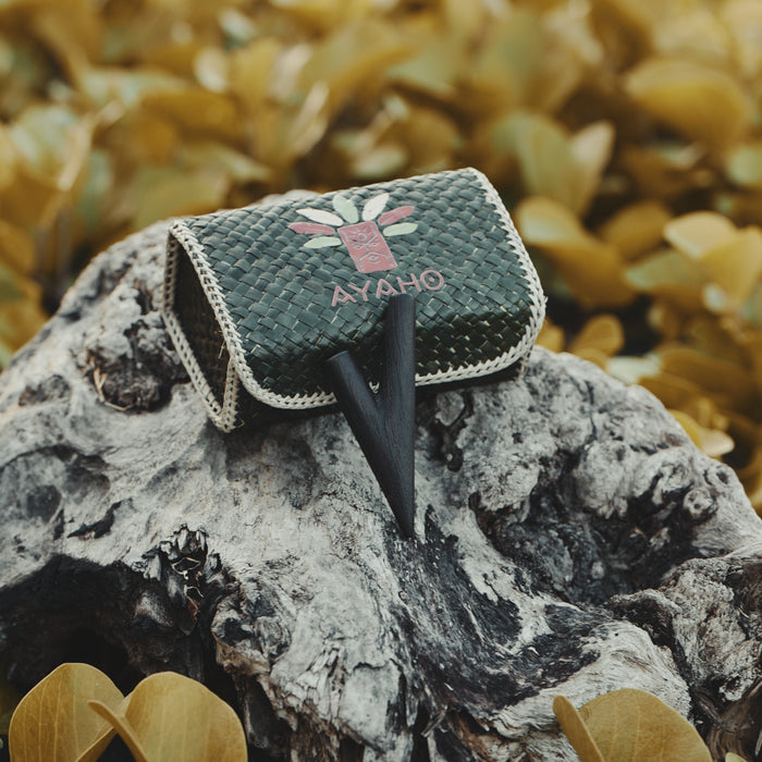 Green quilted bag with 'AYAHO' branding on a textured surface with blurred natural background