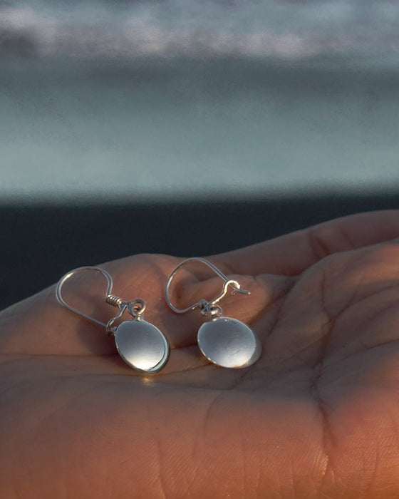 Silver earrings on a hand with a blurred natural background
