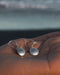 Silver earrings on a hand with a blurred natural background