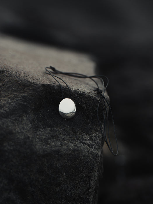 Close-up of a necklace with a pendant on a textured surface