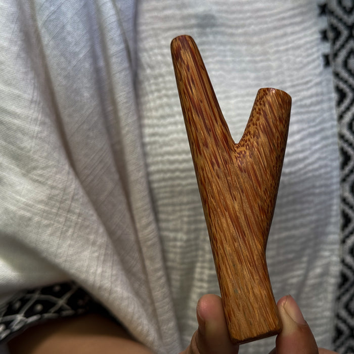 Wooden slingshot held against a textured white background
