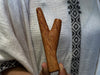 Wooden V-shaped tool held against a patterned fabric background