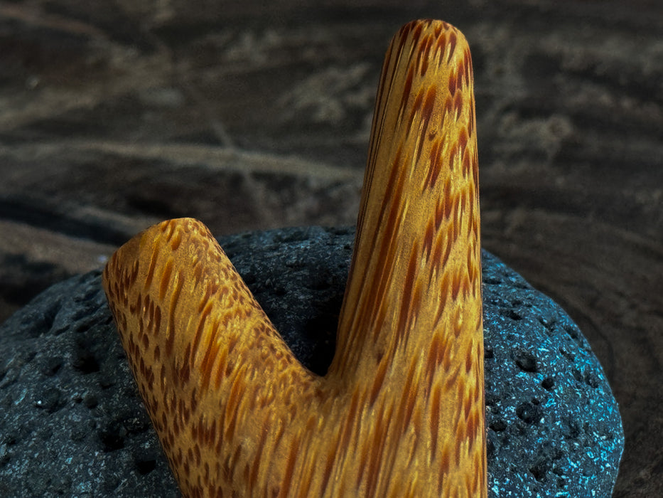 Wooden stirrup on a textured black surface with a blurred brown background
