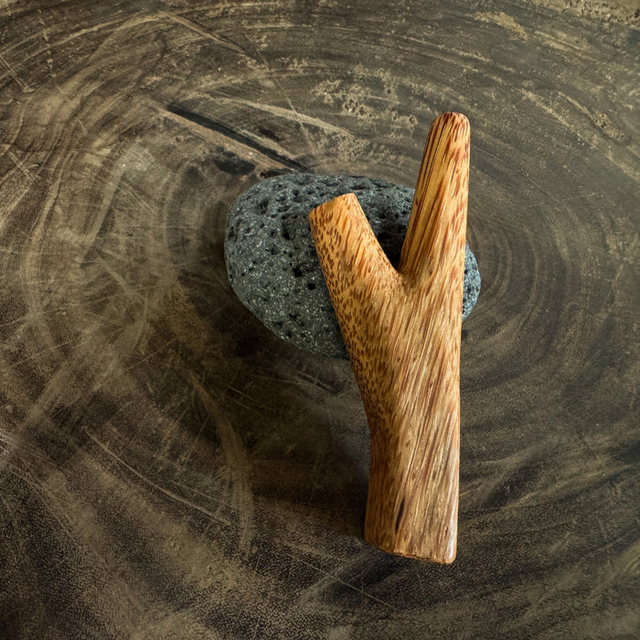 Wooden Y-shaped kuripe on a textured stone surface