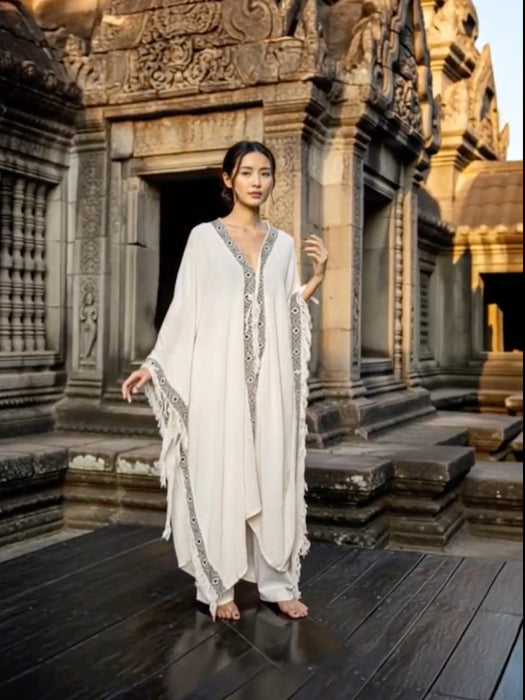 Woman in a white dress standing in front of an ancient temple.