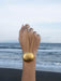 Gold anklet on a foot with ocean in the background