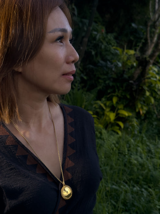 Woman wearing a gold necklace with a dark background