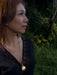 Woman wearing a gold necklace with a dark background